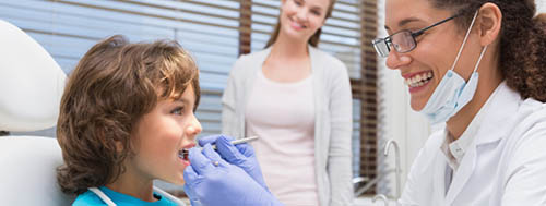 A Dental Hygienist Smiles as She Works on a Childs Mouth