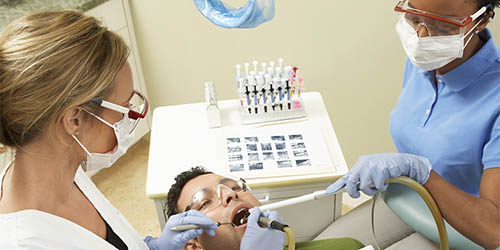 A Dental Hygienist and a Dentist Examine a Patients Mouth